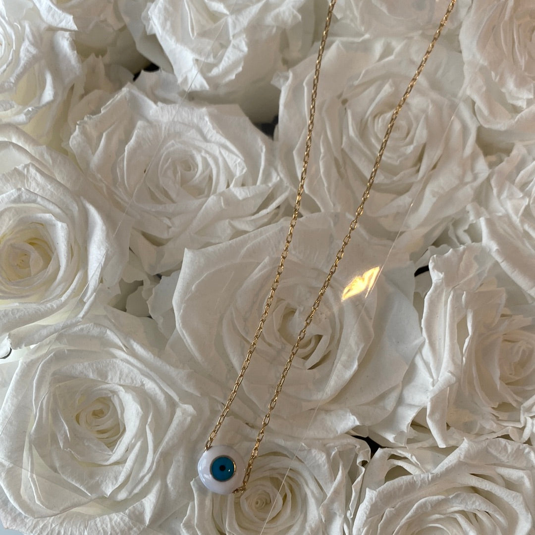 White Evil Eye Necklace on a gold Necklace.