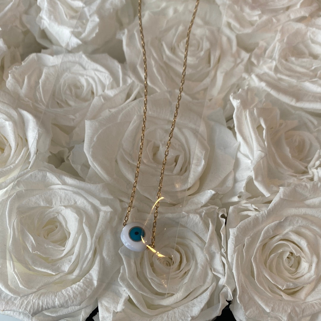 White Evil Eye Necklace on a gold Necklace.